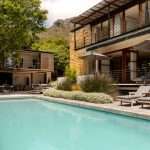 Elegant Cape Town villa with poolside loungers, garden terrace, and mountain views in the background.
