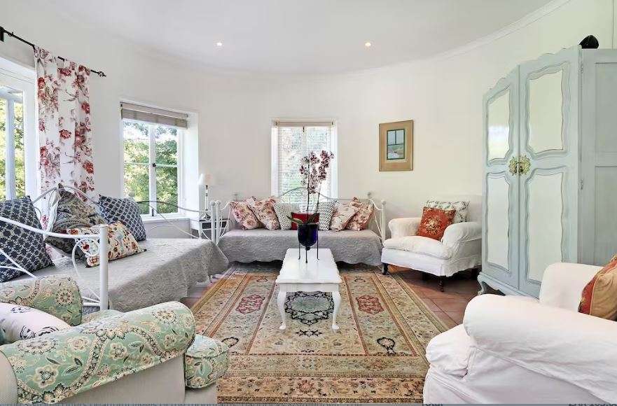 Elegant living room at French Country Silo Villa with vintage furniture, floral textiles, and soft natural light filtering through sash windows.