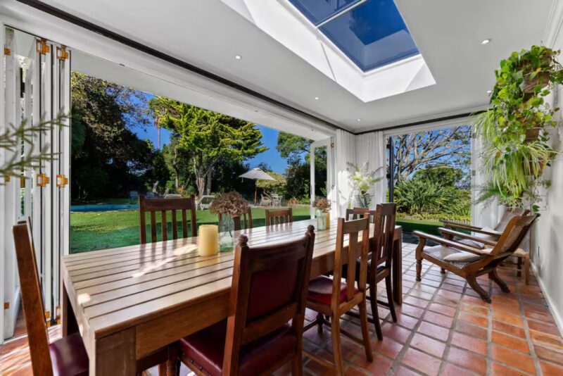 Sun-drenched conservatory dining area with floor-to-ceiling folding doors, skylight ceiling, and seamless connection to the landscaped garden, creating the perfect setting for relaxed family meals and indoor-outdoor entertaining.