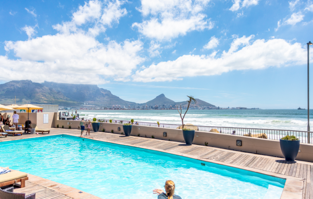 Lagoon Beach Apartment – Spectacular beachfront pool overlooking Table Mountain, Lion's Head, and the Atlantic Ocean, offering one of Cape Town's most iconic coastal settings.