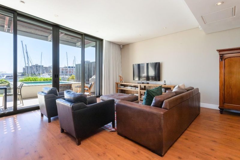 Pembroke 005 – Elegant open-plan living area flowing onto a private terrace with swimming pool, where spectacular views across the V&A Waterfront Marina create a truly exclusive setting.
