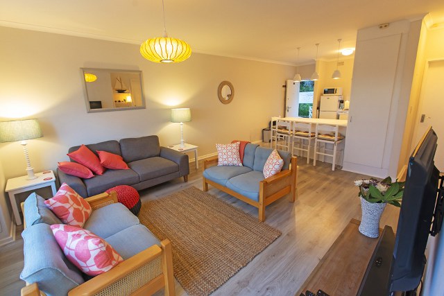 Lazur Holiday Apartment – Bright and welcoming open-plan lounge and kitchen, offering comfortable seating, modern self-catering facilities, and a relaxed space to unwind after a day exploring Wilderness.