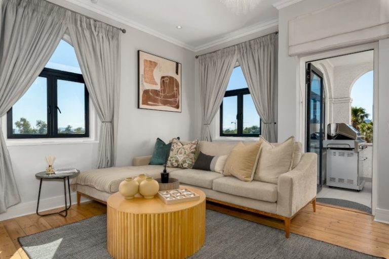 Elegant City Escape – Light-filled lounge with elegant contemporary décor, comfortable seating, and direct access to the spacious entertainment balcony, creating a warm and inviting space to relax after a day exploring Cape Town.