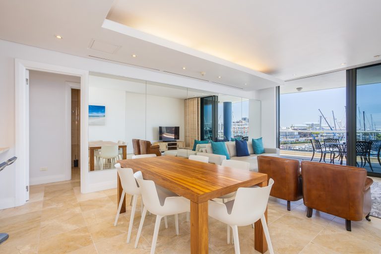 Pembroke 304 – Spacious open-plan living and dining area with elegant contemporary finishes, opening onto a private terrace overlooking the vibrant V&A Waterfront Yacht Basin.