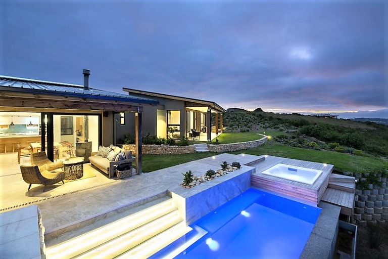 Shufflers – Private pool and jacuzzi illuminated at dusk, with covered outdoor living spaces and the surrounding Knysna landscape creating a peaceful evening setting.
