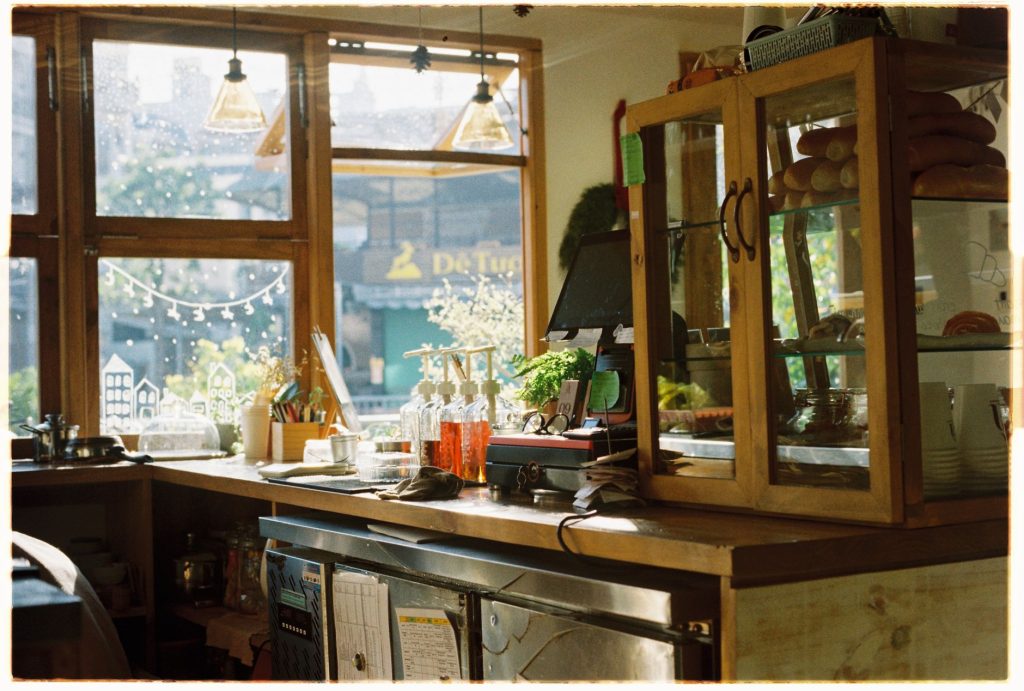 Warm and inviting cafe interior with wooden countertops and sunlight streaming through large windows.