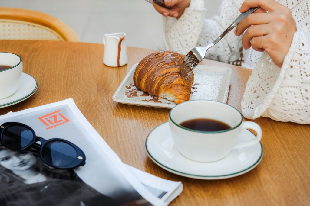 Breakfast with coffee and a chocolate croissant on a café table.