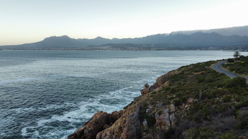 Breathtaking coastal scene with mountains, ocean, and a winding road at dusk.