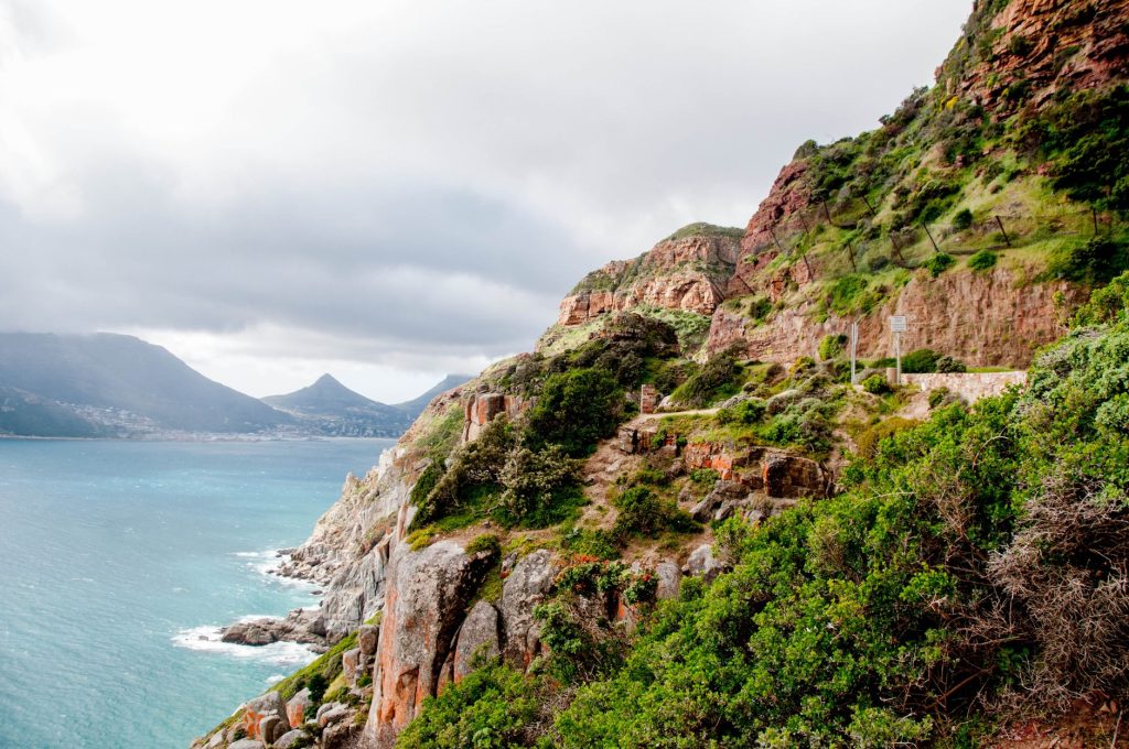 Picturesque view of Cape Town coastline with rocky cliffs and Table Mountain in the distance.