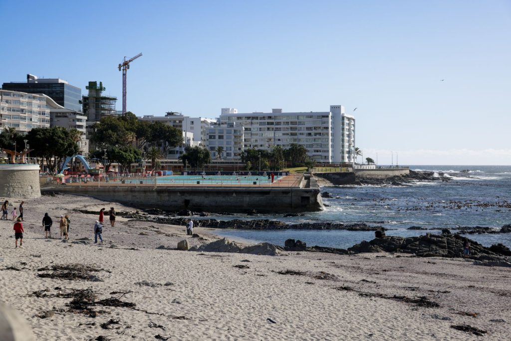 Walkers and runners along a Cape Town seafront promenade with the ocean beside it.