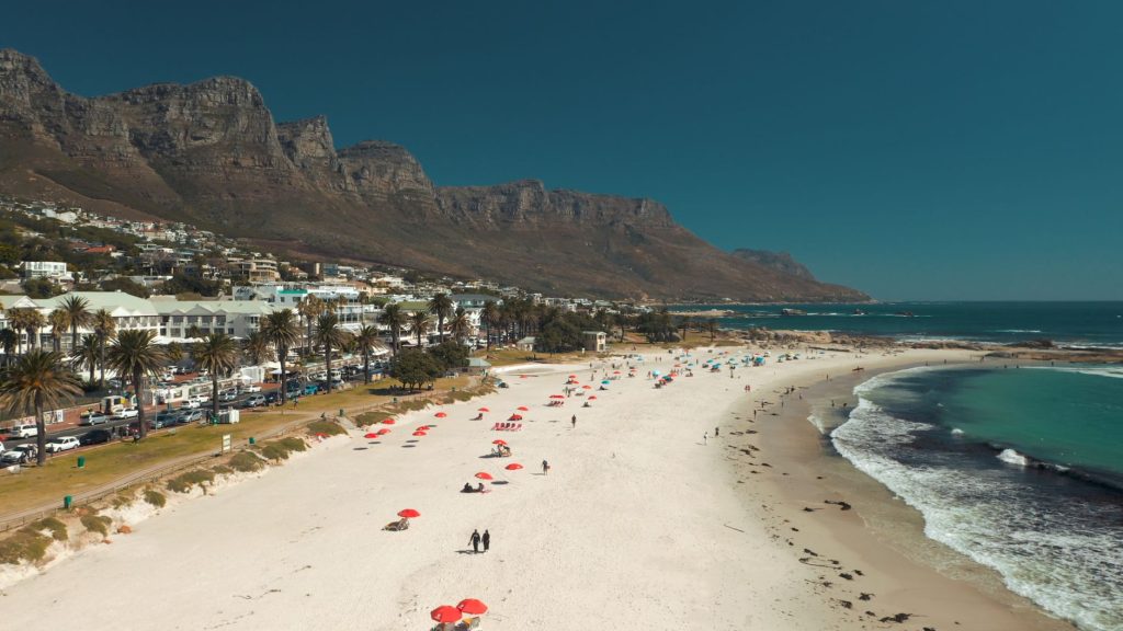 Aerial view of Camps Bay Beach with the Twelve Apostles mountains and the beachfront strip.