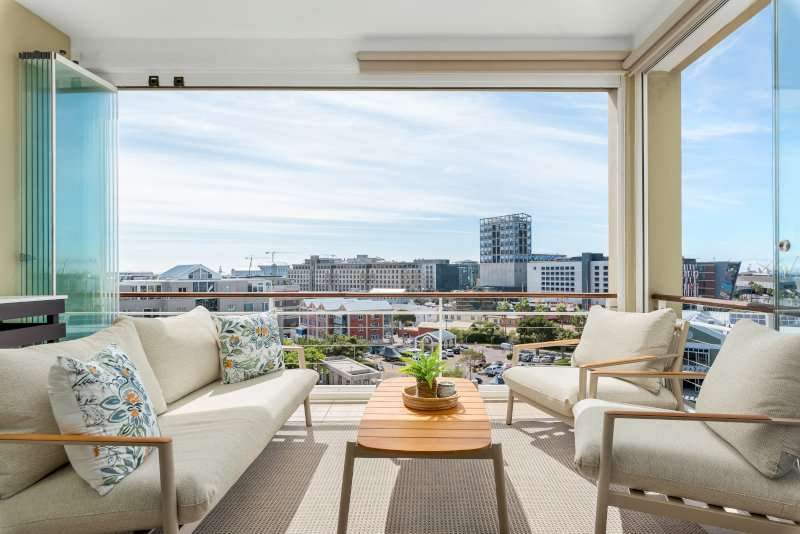 Carradale 3-Bed – Balcony – Bright, comfortable outdoor lounge with glass-enclosed sides and elevated views across the V&A Waterfront precinct.