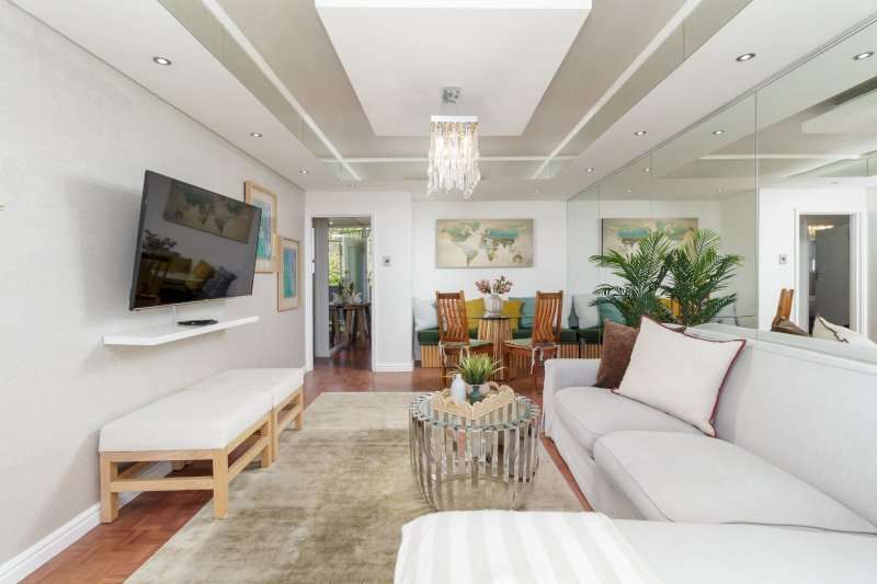 Mouille Point Seaside Stay – Living & Dining Area – Elegant open-plan living space with comfortable seating, a dining area and sophisticated mirrored detailing.