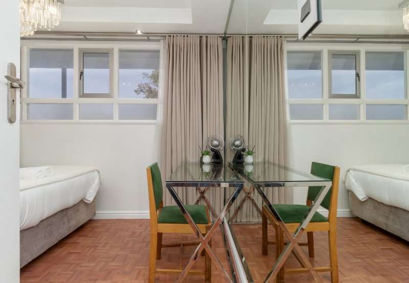 Mouille Point Seaside Stay – Second Bedroom & Workspace – Stylish bedroom with a compact desk and mirrored wall creating a bright and spacious feel.