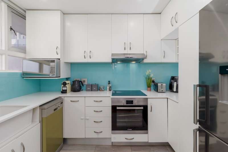 Mouille Point Seaside Stay – Kitchen – Fully equipped modern kitchen with generous cabinetry, quality appliances and a fresh turquoise splashback.
