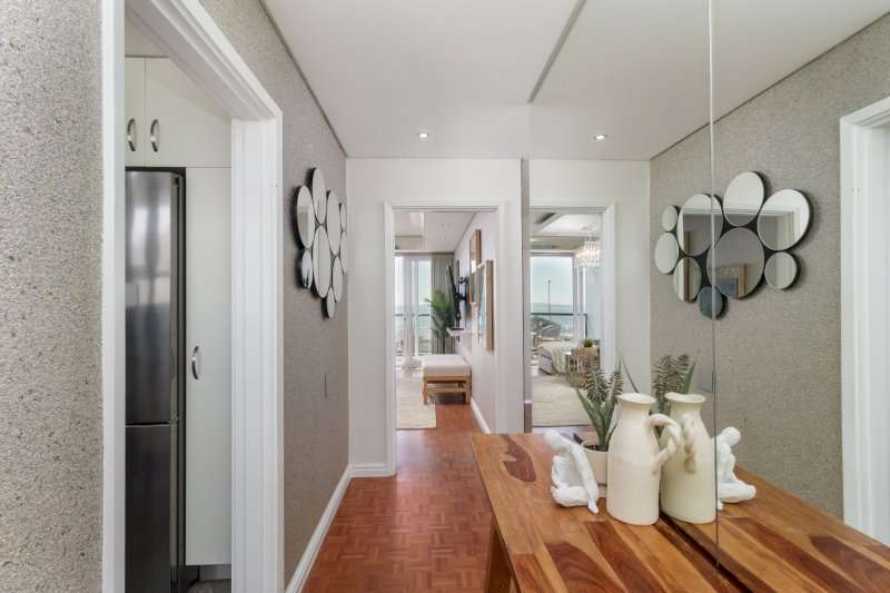 1. Mouille Point Seaside Stay – Entrance Hall – Stylish entrance passage with warm wooden flooring, decorative mirrors and an elegant console leading towards the sea-facing living area.