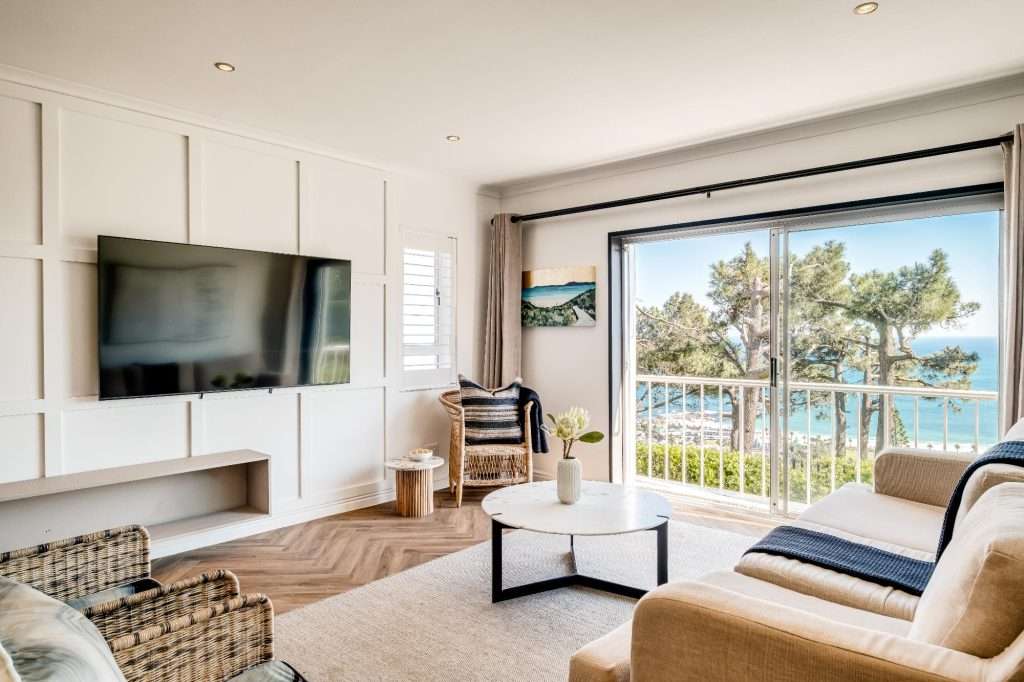 Shoreline Views – Lounge – Bright, contemporary living room with stylish coastal décor, a large TV and beautiful elevated ocean views.