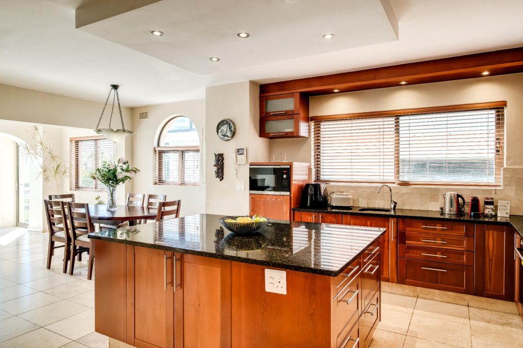 Kaya Eden – Generously sized kitchen with warm timber cabinetry, granite countertops, central island and an adjoining casual dining area.