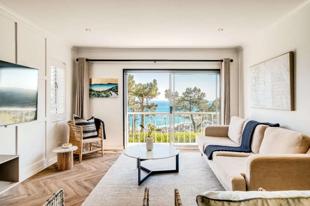 Shoreline Views – Sea-Facing Lounge – Beautifully light-filled living area with floor-to-ceiling sliding doors framing the coastal scenery.