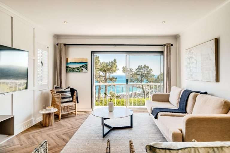 Shoreline Views – Sea-Facing Lounge – Beautifully light-filled living area with floor-to-ceiling sliding doors framing the coastal scenery.