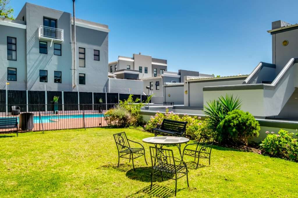 De Waterkant DW-001 – Communal Garden – Peaceful shared garden with lawn, established planting and outdoor seating, offering a lovely space to relax in the sunshine.