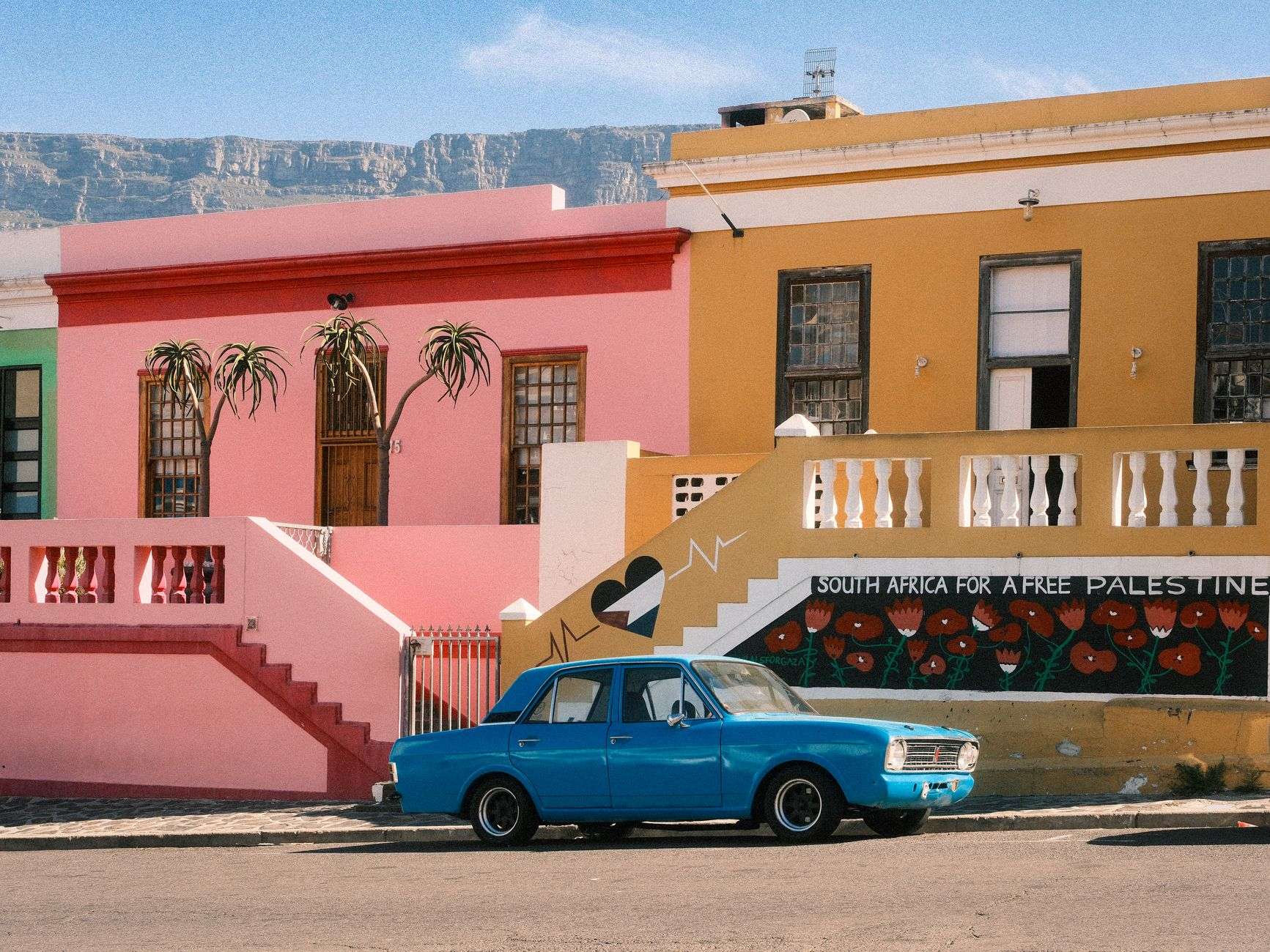 Colourful Bo-Kaap houses in Cape Town with a classic car on a street.