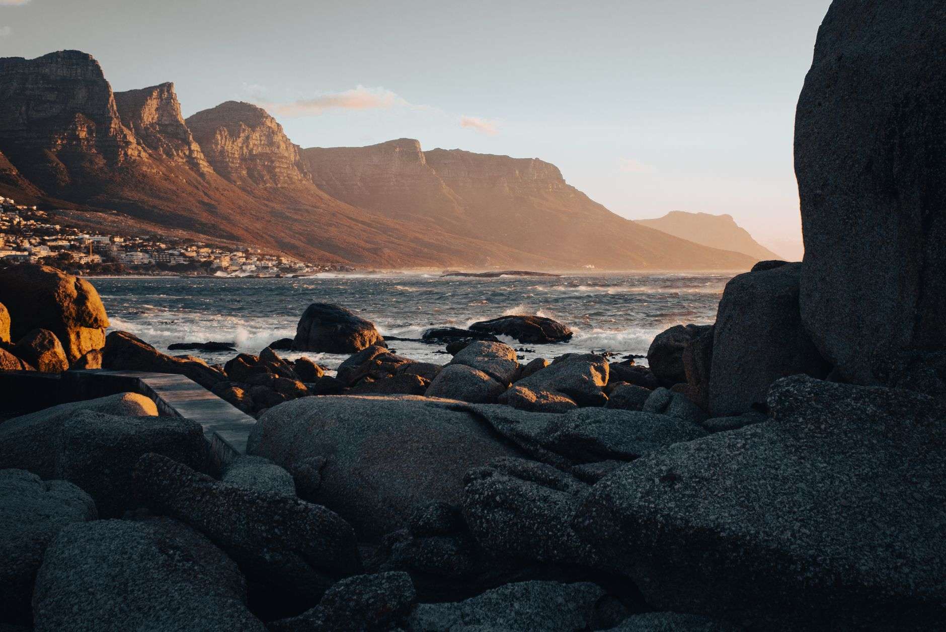 Cape Town’s rocky coastline at sunset with mountains in the background.