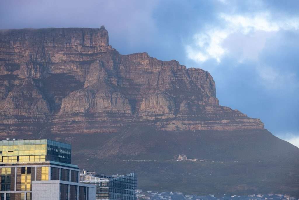 Scenic view of Table Mountain towering over Cape Town, captured at dawn with city buildings in the foreground.