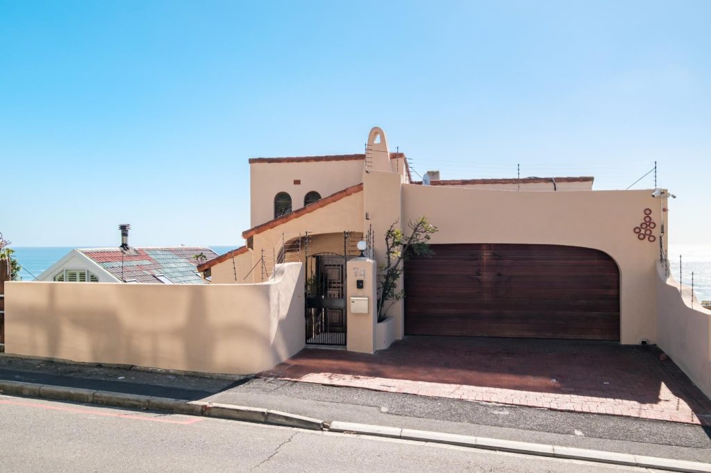 Kaya Eden – Street-facing exterior with secure double garage and distinctive Mediterranean-inspired architecture, with a glimpse of the ocean beyond.
