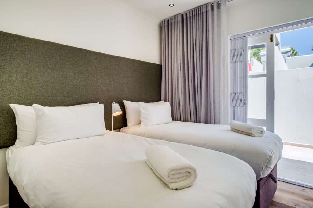 De Waterkant DW-001 – Twin Bedroom – Bright and comfortable twin bedroom with crisp linen and direct access to a small outdoor courtyard.