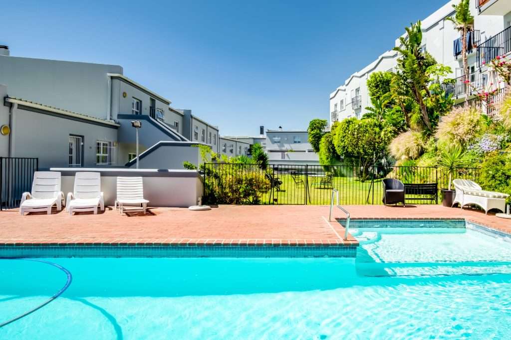 De Waterkant DW-001 – Pool & Gardens – Sunny communal pool area with generous deck space, loungers and attractive garden surroundings.