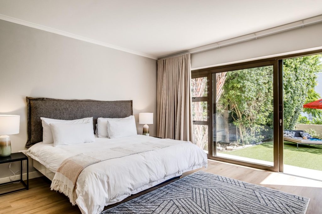 Kaya Eden – Spacious main bedroom with a king-size bed, contemporary neutral décor and large glass doors opening directly onto the private garden.