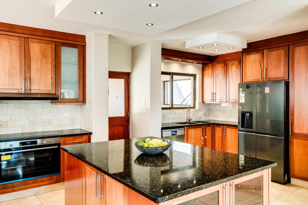 Kaya Eden – Well-appointed kitchen with timber cabinetry, black granite island, integrated appliances and generous preparation and storage space.