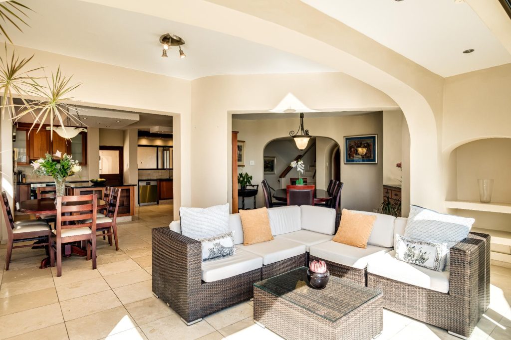 Kaya Eden – Relaxed indoor-outdoor lounge with comfortable wicker seating, flowing open-plan access to the dining and kitchen areas and abundant natural light.