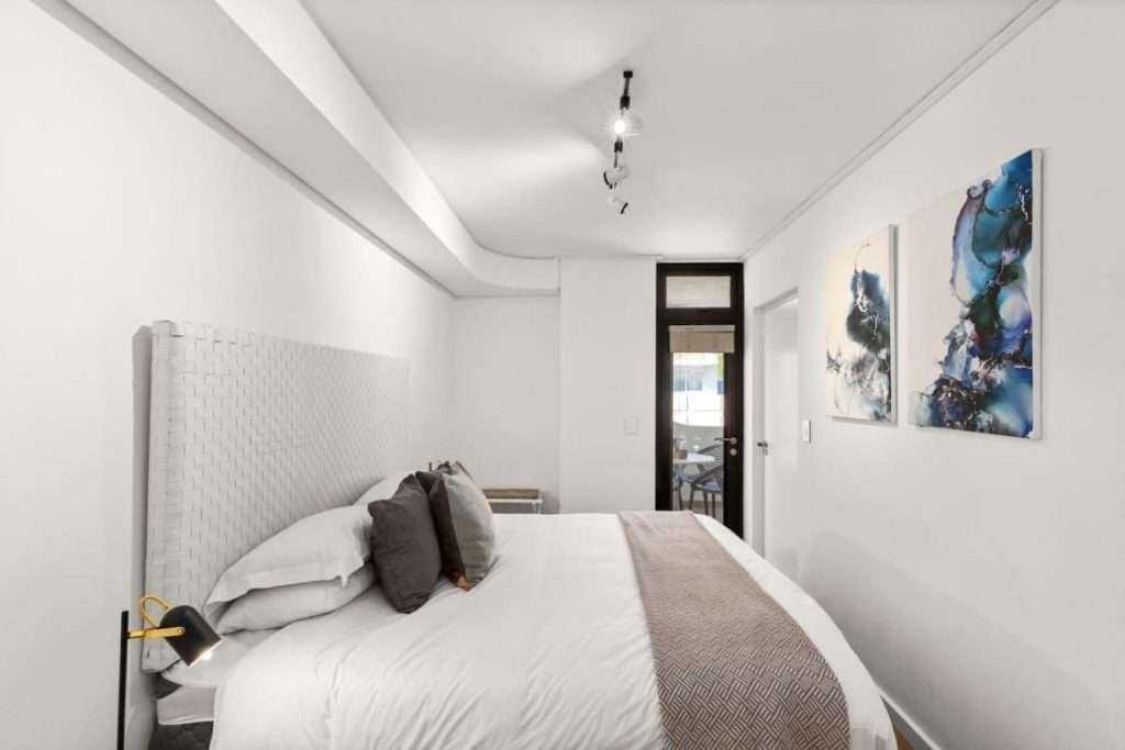 The Tuynhuys – Main Bedroom – Elegant bedroom with a generous bed, upholstered feature headboard and sophisticated neutral styling.