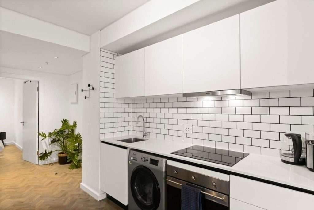 The Tuynhuys – Kitchen – Sleek modern kitchen with integrated appliances, subway-tile splashback, washing machine and everything needed for a comfortable self-catering stay.