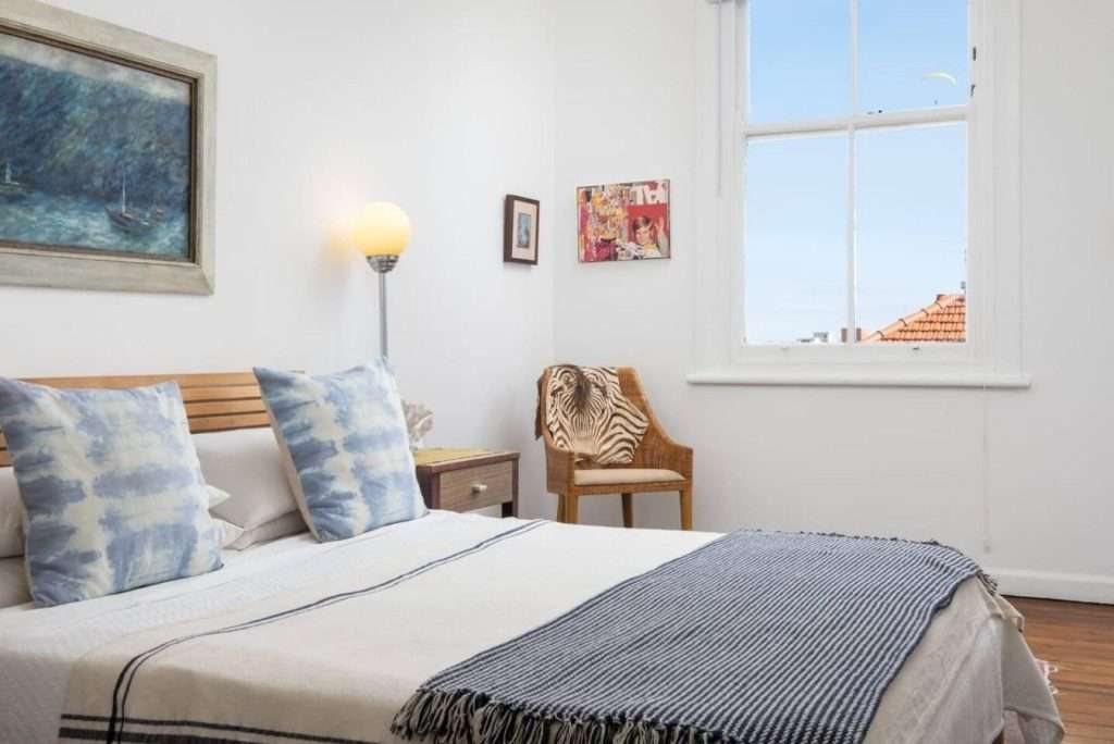 Timeless Sea Point Retreat – Light-Filled Bedroom – Peaceful double bedroom with high ceilings, wooden floors and soft coastal-inspired décor, filled with natural light.