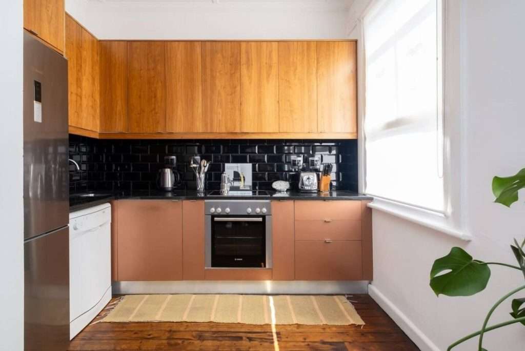 1. Timeless Sea Point Retreat – Fully Equipped Kitchen – Practical contemporary kitchen with warm timber cabinetry, oven, dishwasher, full-size refrigerator and generous natural light.