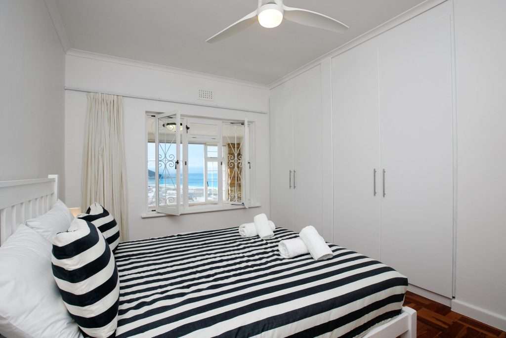 The Perch – Bedroom with Sea View – Bright double bedroom with crisp coastal styling, ample built-in cupboards and beautiful views towards the ocean.