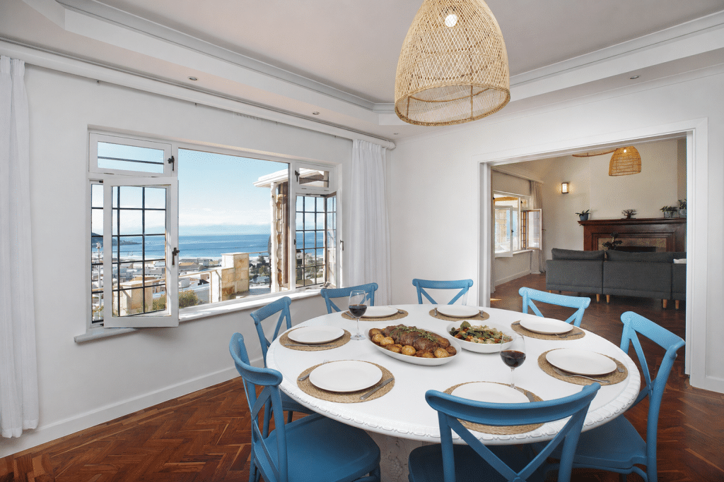 The Perch – Dining with a View – Inviting dining area seating eight, with wide windows framing spectacular sea and mountain scenery.