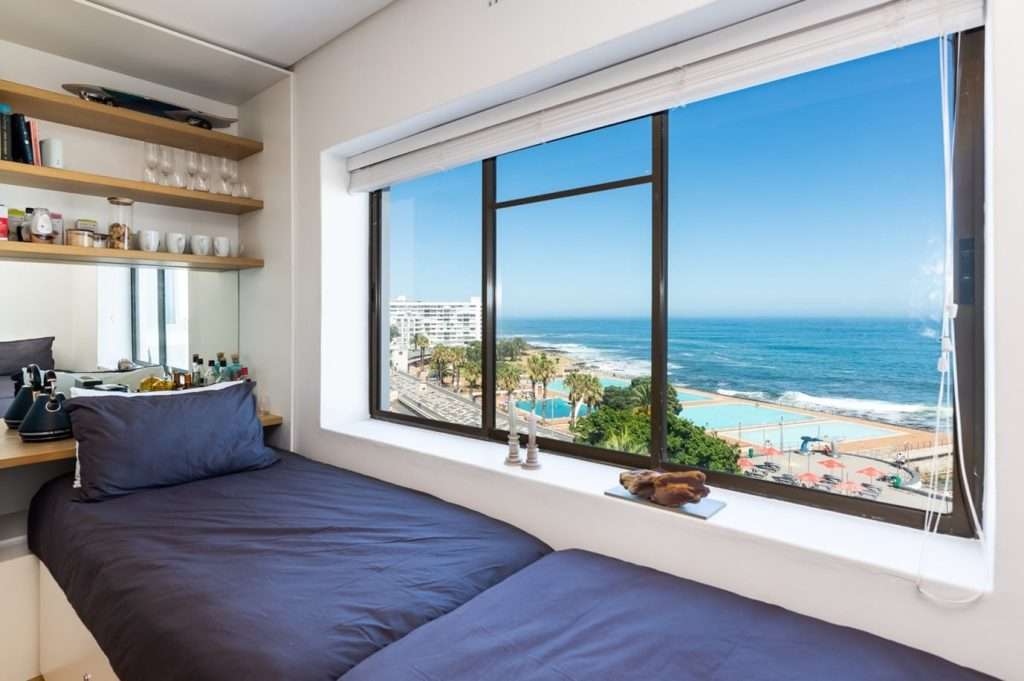 Mimosa Views – Cosy window-side lounging area offering magnificent views of the Atlantic Ocean, Sea Point Promenade and the iconic Sea Point Pavilion swimming pools.