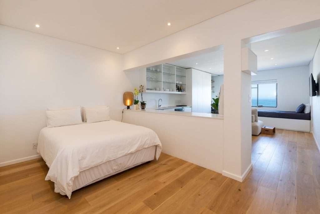 Mimosa Views – Bright and airy open-plan sleeping area featuring a comfortable double bed, warm wooden flooring and a contemporary kitchen, with a separate lounge overlooking the Atlantic Ocean.