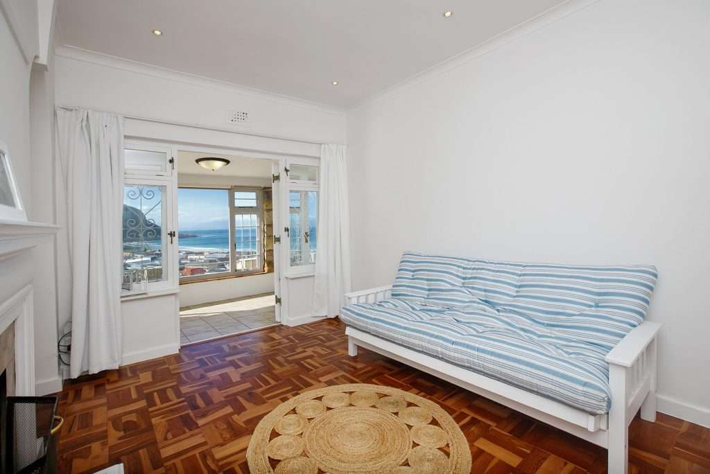 The Perch – Additional Living Area – Relaxed second living space with warm parquet flooring and coastal styling, opening towards beautiful elevated sea views.