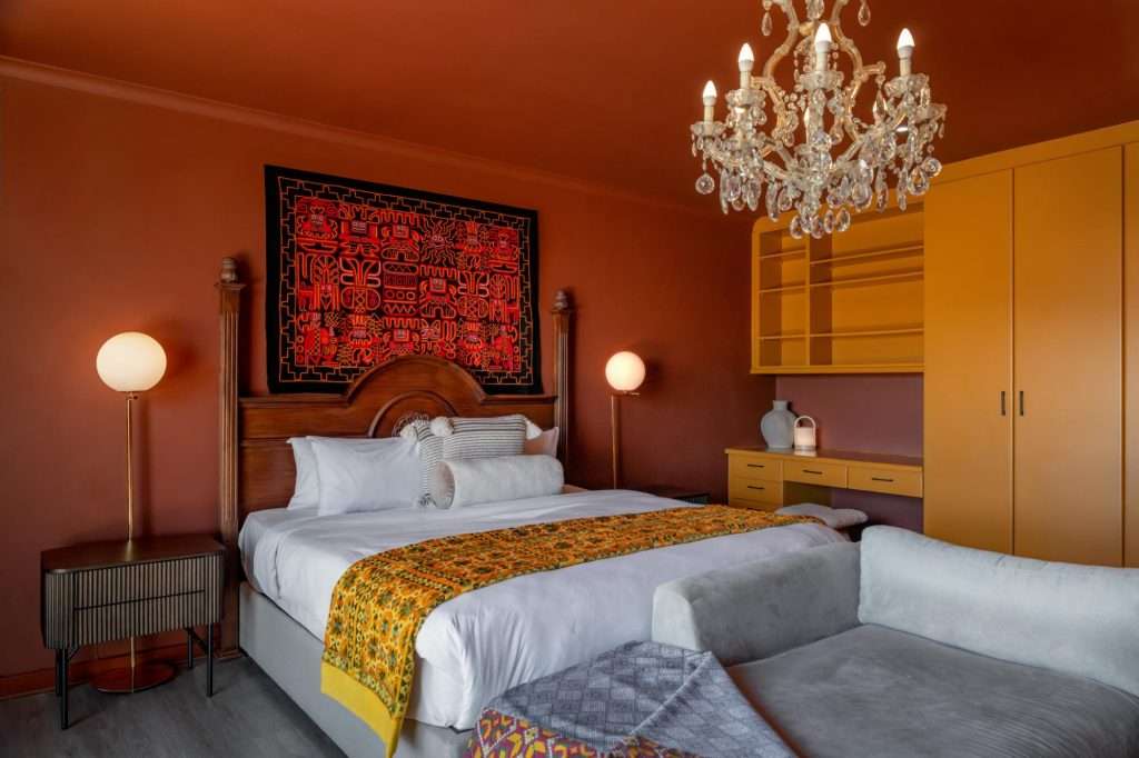 Kinvara Villa – Statement Bedroom – Rich terracotta tones, a crystal chandelier and bold African-inspired textiles create a warm, characterful bedroom retreat.