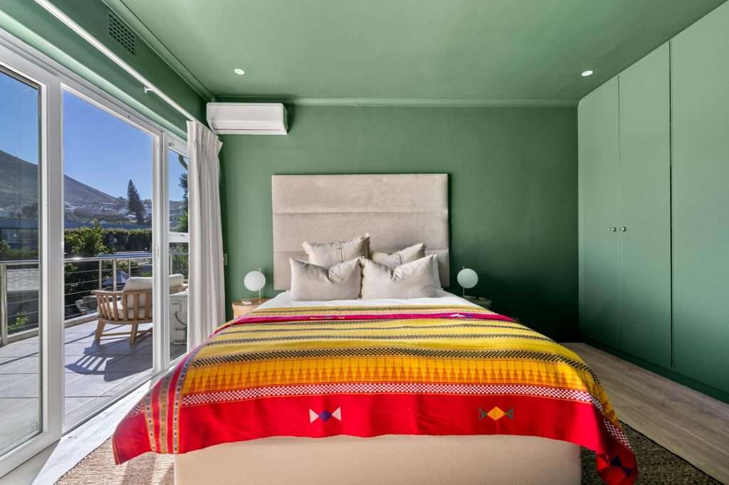Kinvara Villa – Green Bedroom – Stylish bedroom in calming green tones, opening through glass doors onto a sunny private terrace.