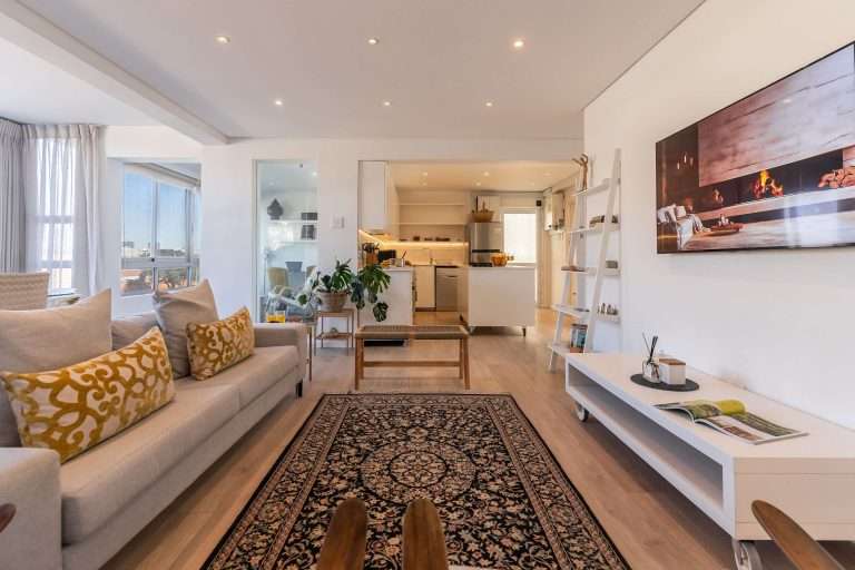 Protea Views Apartment – Spacious open-plan lounge with comfortable seating, a wall-mounted television, stylish décor and easy access to the modern kitchen.
