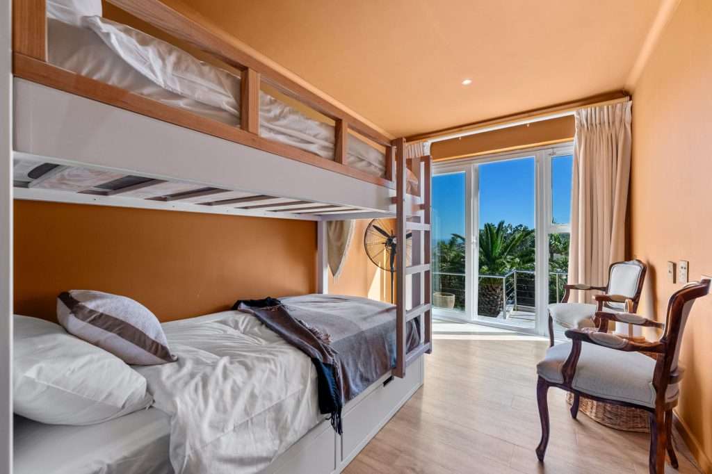 Kinvara Villa – Bunk Bedroom – Comfortable bunk room with warm earthy tones and direct access to an outdoor balcony, ideal for younger guests.