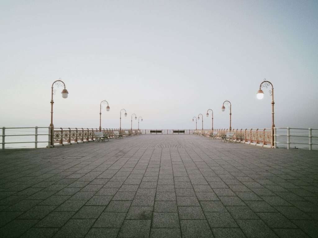 Empty coastal pier with promenade lamps by the sea.