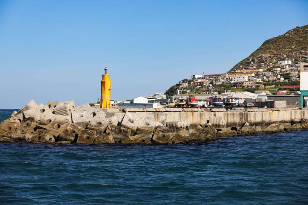 Vibrant harbor scene in Hout Bay, Cape Town, showcasing colorful buildings and ocean waves.