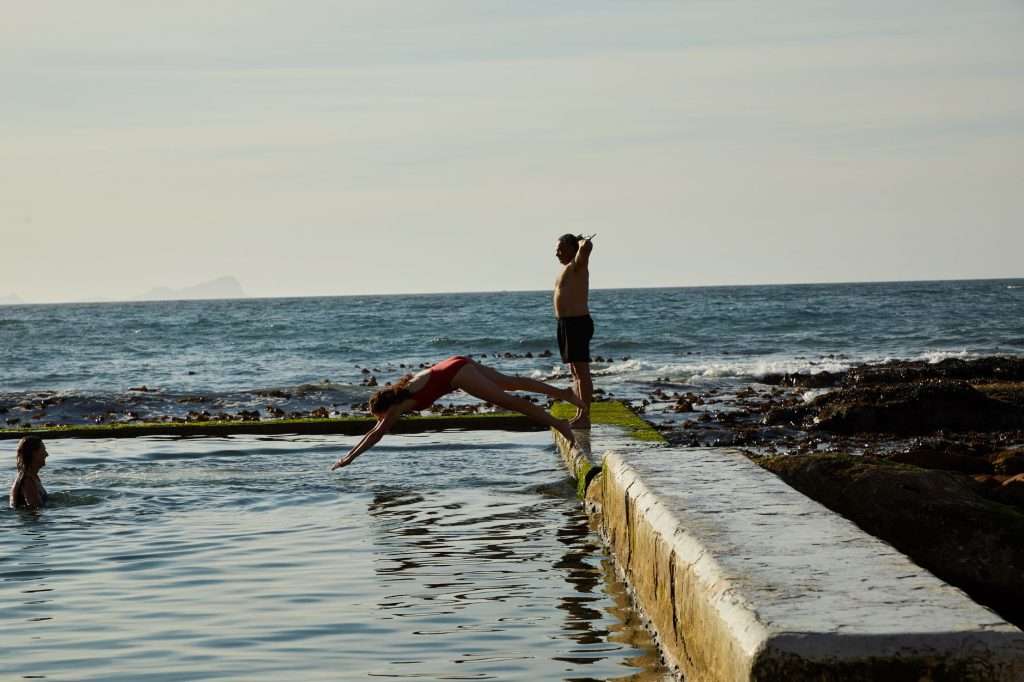 Families paddling in a sheltered tidal pool at the coast.
